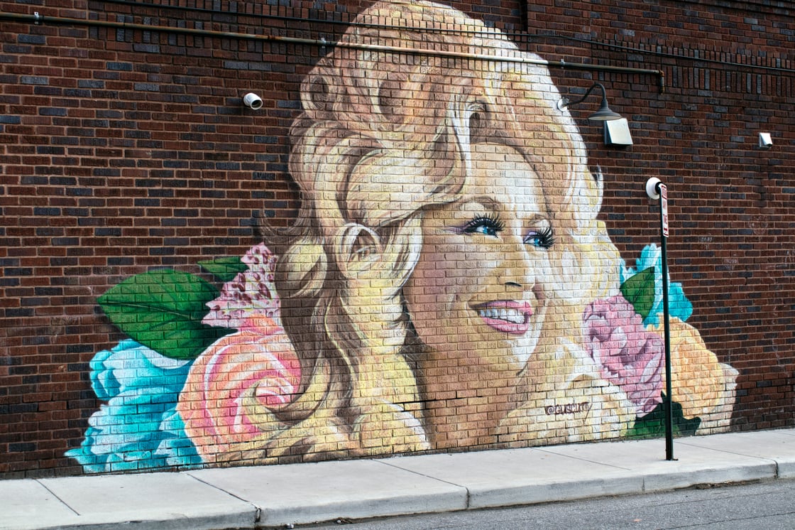 Image of a Dolly Parton mural on a brick wall